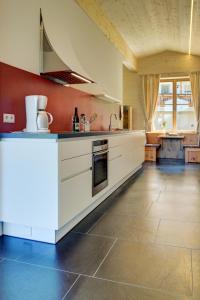 a large kitchen with white cabinets and a tile floor at Ratzeshof in Castelrotto