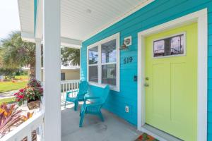 a blue house with a yellow door and two chairs at Blu Star Oasis Beach Htd Pool Pets Firepit in Saint Augustine