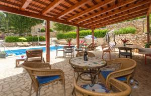 eine Terrasse mit Tischen und Stühlen und einem Pool in der Unterkunft Villa Brkic with large private pool and playground in Brkići