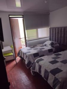 a bedroom with a bed with a checkered blanket at Casa frente Universidad de Manizales 4 habitaciones cerca al centro de la ciudad in Manizales