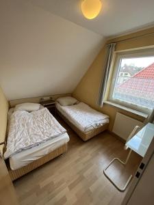 two beds in a small room with a window at Haus Delphin - Ferienwohnung 1 in Norderney