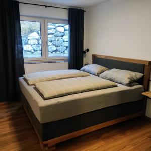 uma cama grande num quarto com 2 janelas em Ferienwohnung Lehmann em Blaichach