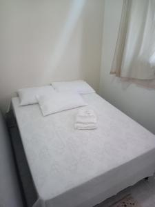 a white bed in a room with a window at Espaço do Adilson é aconchegante in Rio de Janeiro
