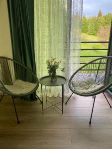 two chairs and a table in front of a window at Duplex apartment near the forest in Bakuriani