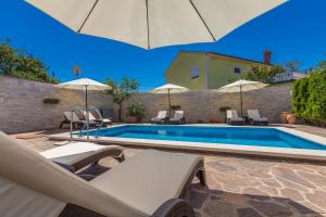 een zwembad met stoelen en parasols naast een huis bij Guest House Antonella in Malinska
