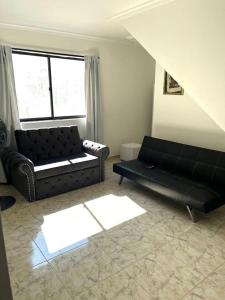 a living room with two black couches and a window at Apartamento Vacacional Cartagena Colombia in Cartagena de Indias