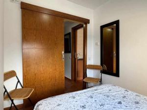 a bedroom with a bed and two chairs and a door at Apartamento Girasol in Sierra Nevada