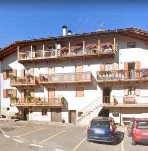 a building with balconies and cars parked in a parking lot at Appartamento Travai in Predazzo