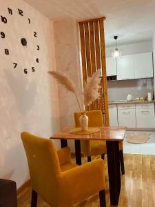 a dining room with a wooden table and yellow chairs at Apartman Royal 4 in Doboj