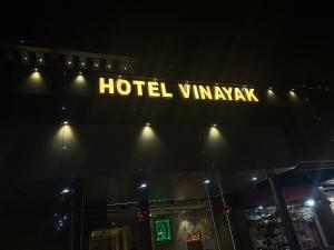 un panneau d'hôtel sur le côté d'un bâtiment la nuit dans l'établissement Hotel Vinayak, à Kharagpur