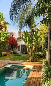 a swimming pool in front of a house with palm trees at Villa Vicuña Hotel Boutique in Salta