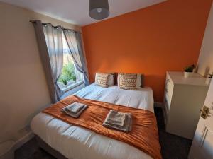 a bedroom with a bed with orange walls and a window at Beacon House in Leicester