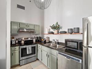 una cocina con armarios verdes y electrodomésticos de acero inoxidable en Downtown Condo, en Cleveland