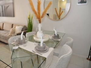 einen Glastisch mit Stühlen und einem Spiegel im Wohnzimmer in der Unterkunft Elcaro Luxury Villas-Urban Taupe in Midrand