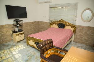 a bedroom with a bed and a flat screen tv at 7 Palms Bungalow in Accra