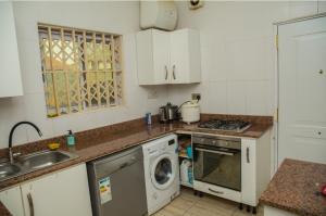 uma cozinha com um lavatório e uma máquina de lavar roupa em 7 Palms Bungalow em Acra