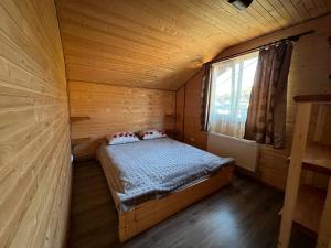 ein kleines Zimmer mit einem Bett in einer Holzhütte in der Unterkunft Шпінь 2 in Worochta