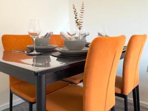 a dining room table with orange chairs around it at Spacious Duplex Near the University and Bodleian Library in Oxford