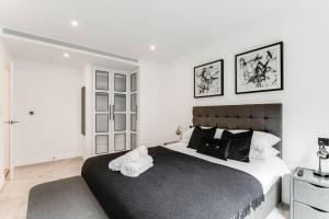 a bedroom with a large bed with two towels on it at Chic Chelsea 1BR Luxe Retreat, Serene Balcony in London