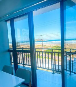 a room with a view of the ocean from a balcony at Apto Pé na Areia com Piscina Privativa in Imbituba