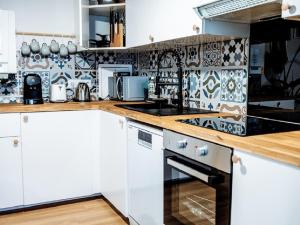 a kitchen with white cabinets and blue and white tiles at OASIS - 10 min from Disney, Free Parking, Self-Checkin in Montévrain