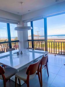 a dining room with a white table and chairs at Apto Pé na Areia com Piscina Privativa in Imbituba +46 photos