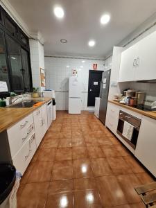 a large kitchen with white cabinets and a tile floor at BBTK Bed and Bike in Málaga