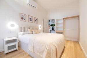 a white bedroom with a white bed and a window at Loft Playa Samil in Vigo
