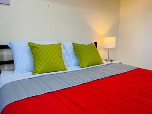 Cama con manta roja y almohadas verdes en The Rainier Bed & Breakfast 5, en San José