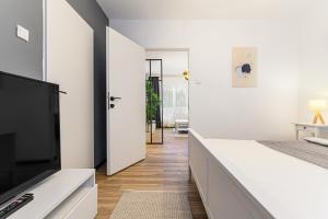 a bedroom with white walls and a flat screen tv at Travelers Hideout - Central Apartment in Braşov