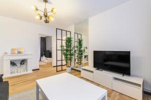 uma sala de estar com uma televisão e uma mesa branca em Travelers Hideout - Central Apartment em Brasov