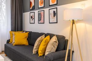 a living room with a gray couch with yellow pillows at Travelers Hideout - Central Apartment in Braşov