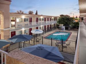 einen Balkon mit Tischen und Sonnenschirmen sowie einem Pool in der Unterkunft Dream Inn in Fresno