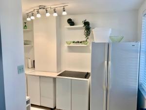 a white kitchen with a refrigerator and shelves at New ATL Dwntwn Condo with Balcony 2 in Atlanta