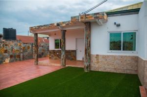 uma casa com um pátio com relva verde em 7 Palms Bungalow em Acra