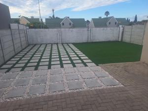 a backyard with a fence and a green lawn at Serendip@sea in Cape Town +2 photos