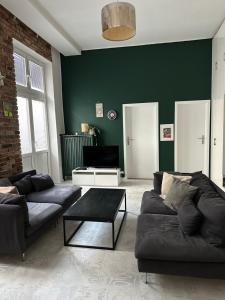 uma sala de estar com dois sofás e uma parede verde em P-122 Piotrkowska Apartment. em Lódź