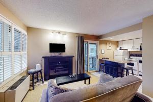 a living room with a couch and a table and a kitchen at Condo 503 at North Creek Resort in Blue Mountains