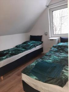 two beds sitting in a room with a window at Izery Apartamenty in Szklarska Poręba