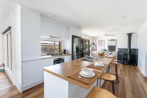 a kitchen with white cabinets and a wooden table at Pet Friendly 3 bedroom house with large backyard in Clifton Springs