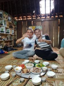 two men sitting on the floor with plates of food at Ha Giang Yolo House and Loop Tours in Ha Giang