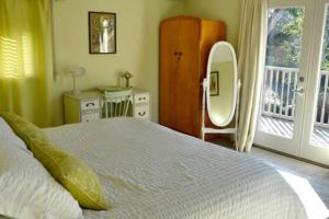 Schlafzimmer mit einem Bett, einem Spiegel und einem Fenster in der Unterkunft French Beach House Shirley BC in Shirley