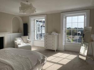 a bedroom with a bed and a chair and windows at No.8 Laura Place in Aberystwyth