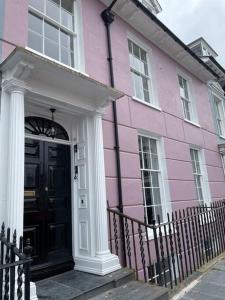 una casa rosa con una puerta negra y ventanas en No.8 Laura Place en Aberystwyth