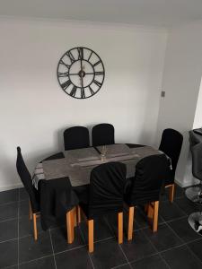a dining room table with chairs and a clock on the wall at Eden Stays in Stivichall
