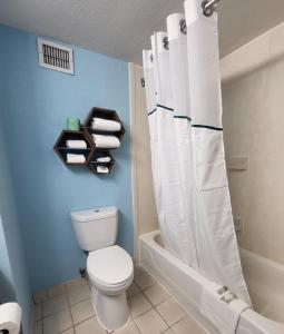 a bathroom with a toilet and a bath tub with a shower curtain at HomeTowne Studios by Red Roof Prattville in Prattville