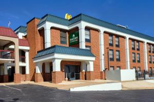 a red brick building with a sign on it at HomeTowne Studios by Red Roof Prattville in Prattville