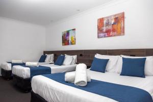 Una fila de cuatro camas en una habitación en Matilda Motor Inn, en Dubbo