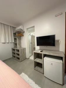 a bedroom with a tv and a desk with a television at Pousada Renda do Mar in Morro de São Paulo