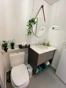 a white bathroom with a toilet and a mirror at Apartamento Novo Moderno-8Km Aeroporto GRU in Guarulhos